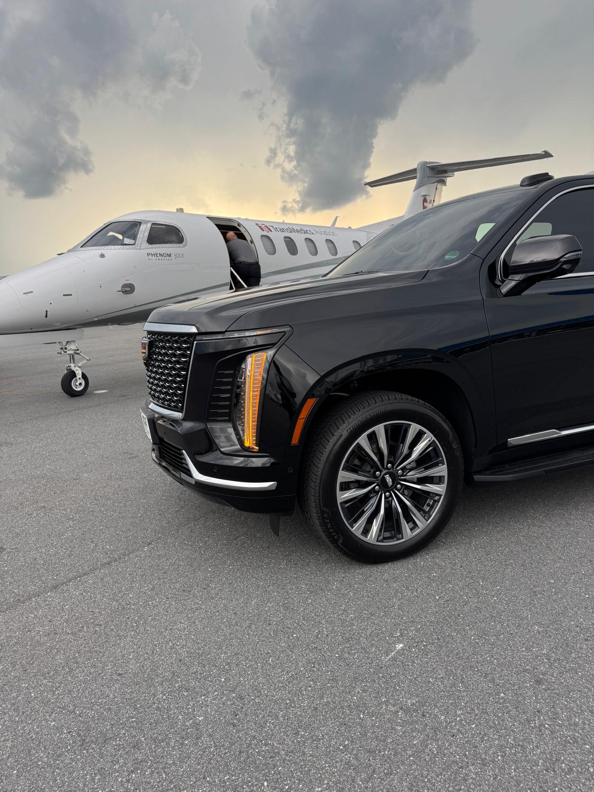 Black Cadillac Escalade beside a private jet for executive chauffeur service in Houston