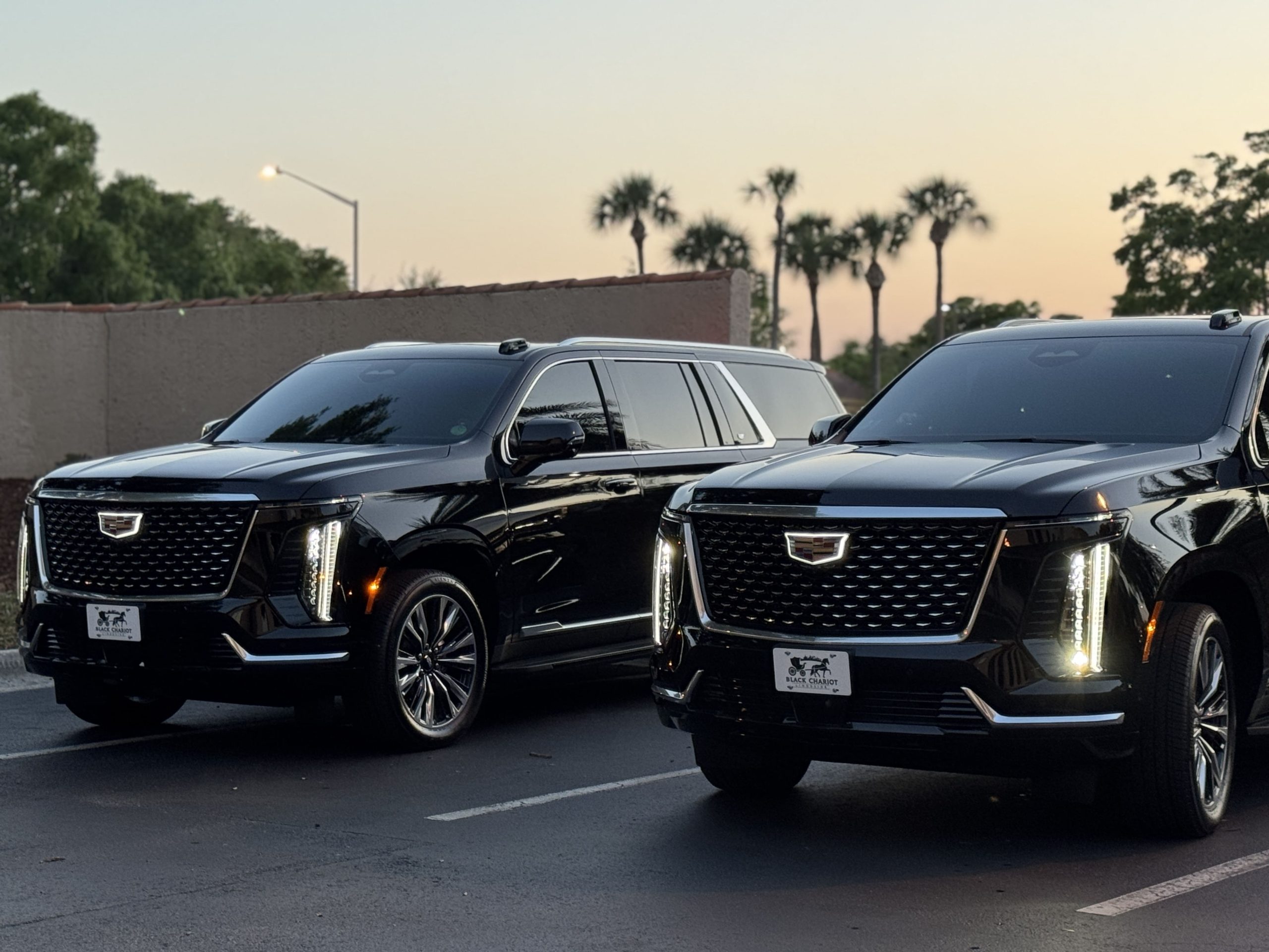 Black Cadillac Escalade on a tree-lined Orlando resort drive for theme park transportation